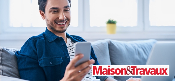 homme assis sur son canapé qui regarde son téléphone en souriant