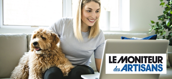 jeune femme assise sur son canapé qui regarde son ordinateur avec son chien à coté